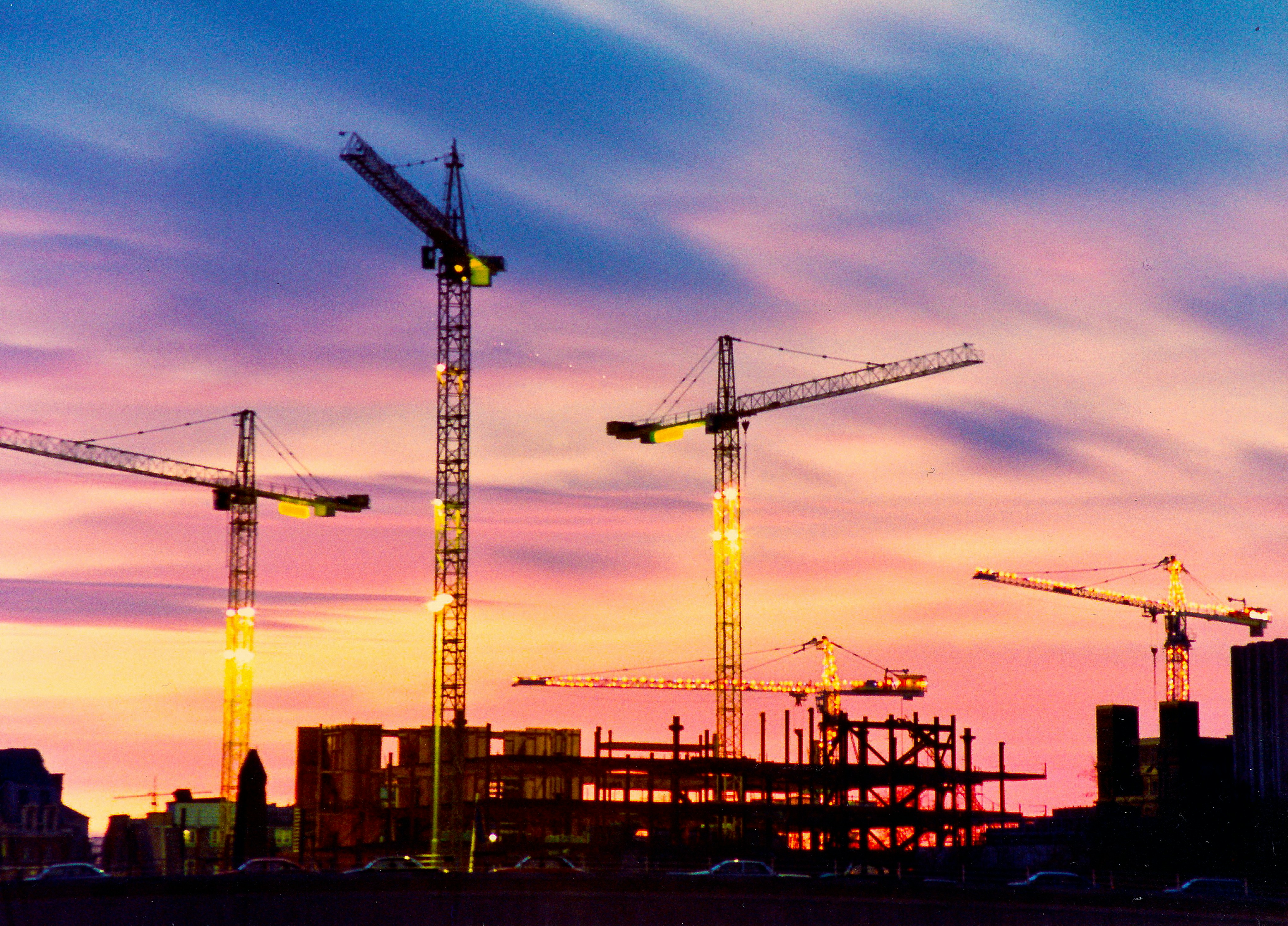Construction site with scaffolding and crane at sunset
